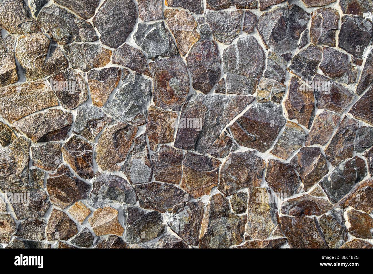 Primo piano di sfondo con texture murale in pietra irregolare. Primo piano di una parete irregolare in pietra naturale con consistenza ruvida e giunti di Malta, ideale come un Foto Stock