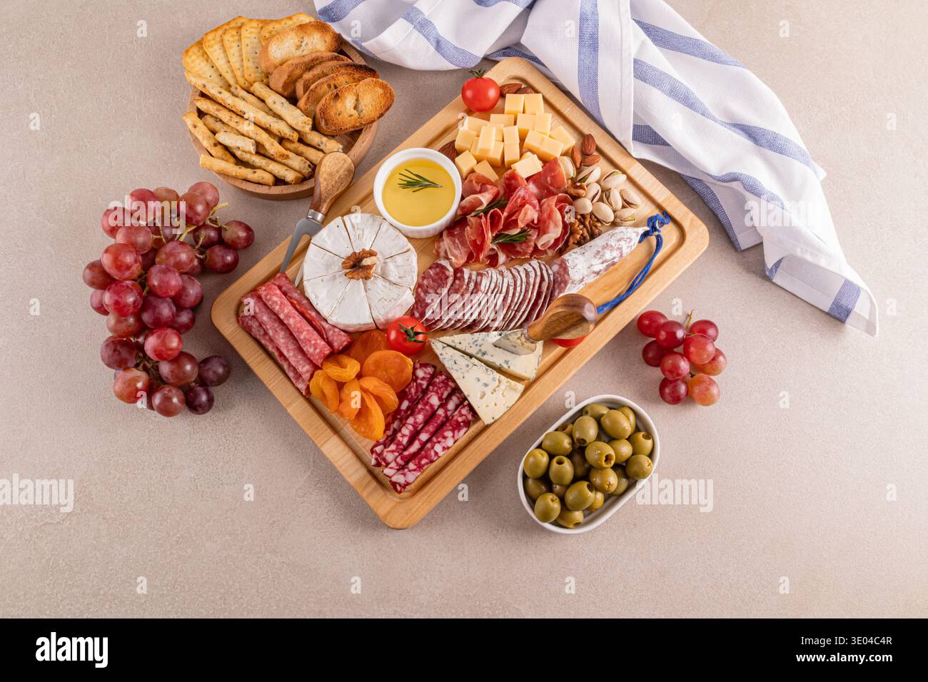 Un delizioso piatto di formaggi con una varietà di formaggi, affettati, uva fresca, frutta secca assortita e olive. Perfetto per riunioni eleganti e Foto Stock