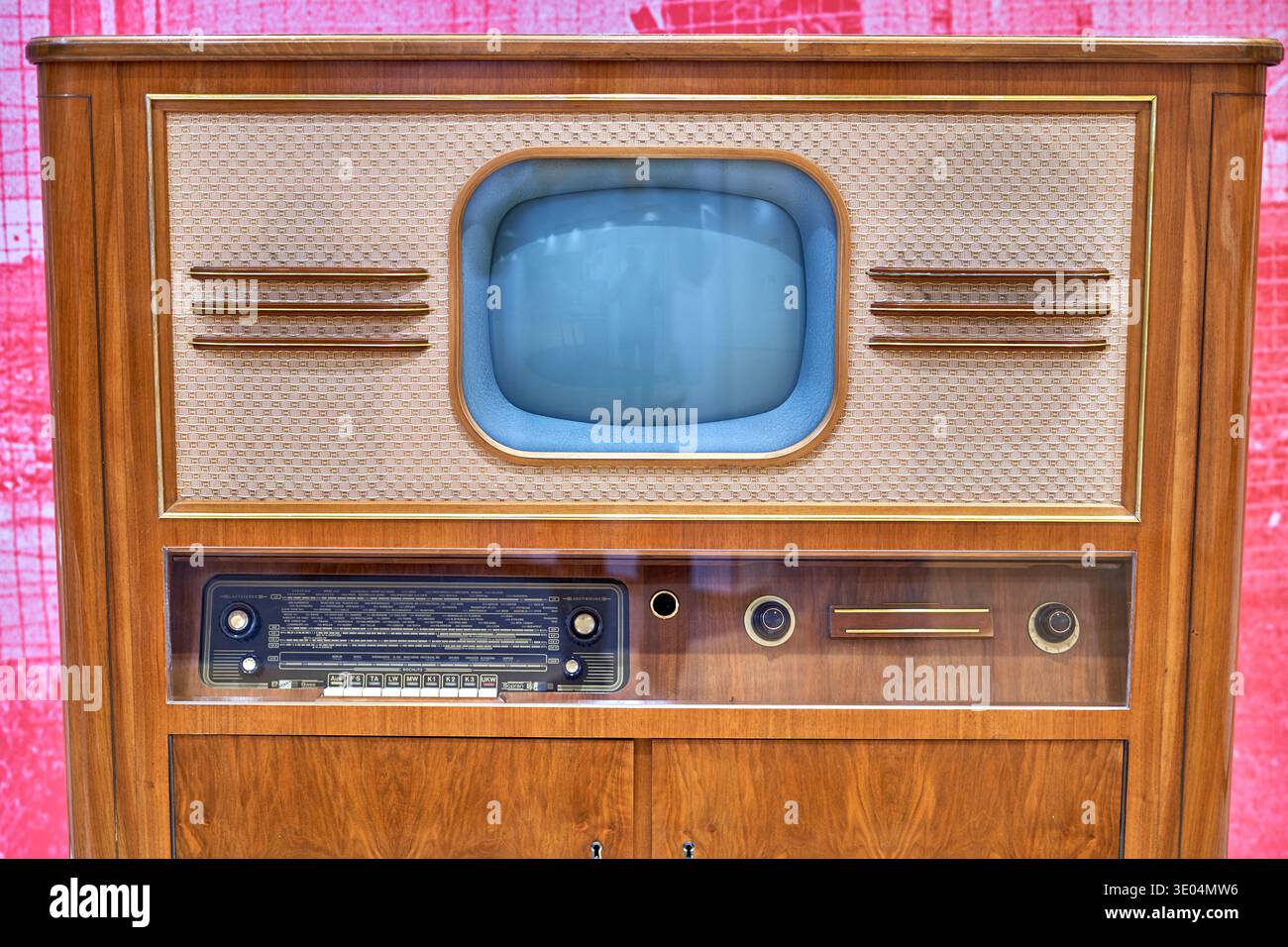 Un televisore a console in legno d'epoca e un set di combinazione radio della metà del XX secolo, esposto su uno sfondo a motivi rosa. L'unità... Foto Stock