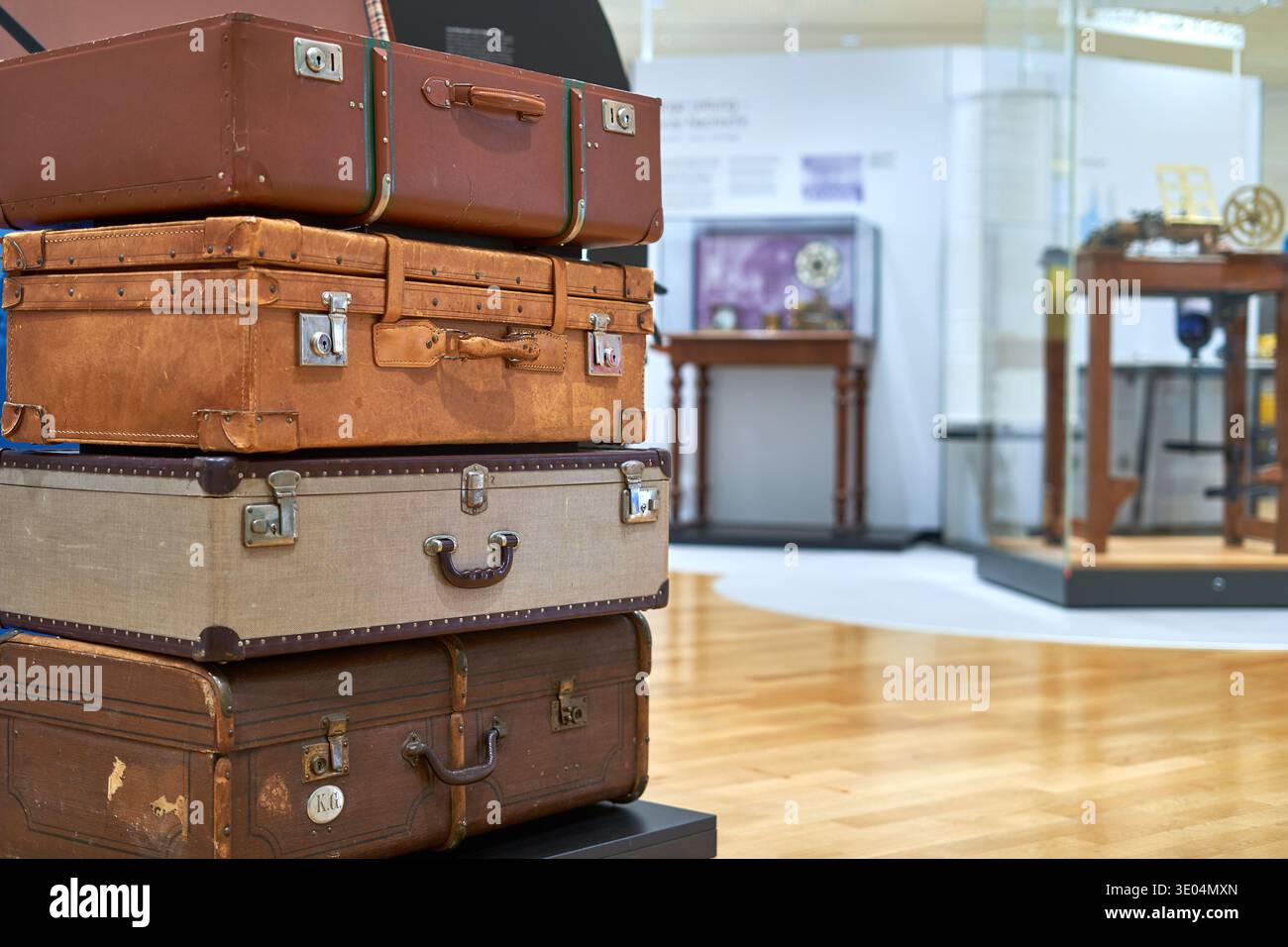 Una pila di quattro valigie vintage esposte in uno spazio espositivo del museo. I bagagli variano in dimensioni, colore e materiale, tra cui... Foto Stock
