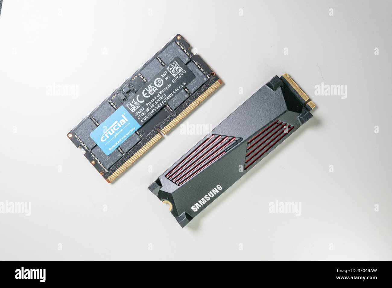 Primo piano del modulo di memoria SODIMM DDR5 Crucial e dell'unità a stato solido Samsung NVMe, che mostra i componenti hardware del computer a fronte di un surfac bianco pulito Foto Stock