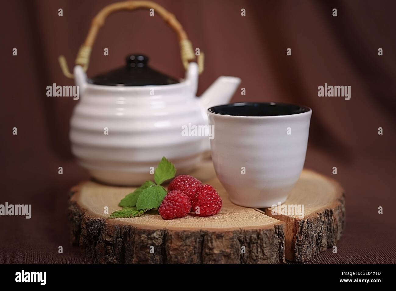 una teiera e una tazza per una persona accanto ad essa giacciono i lamponi Foto Stock