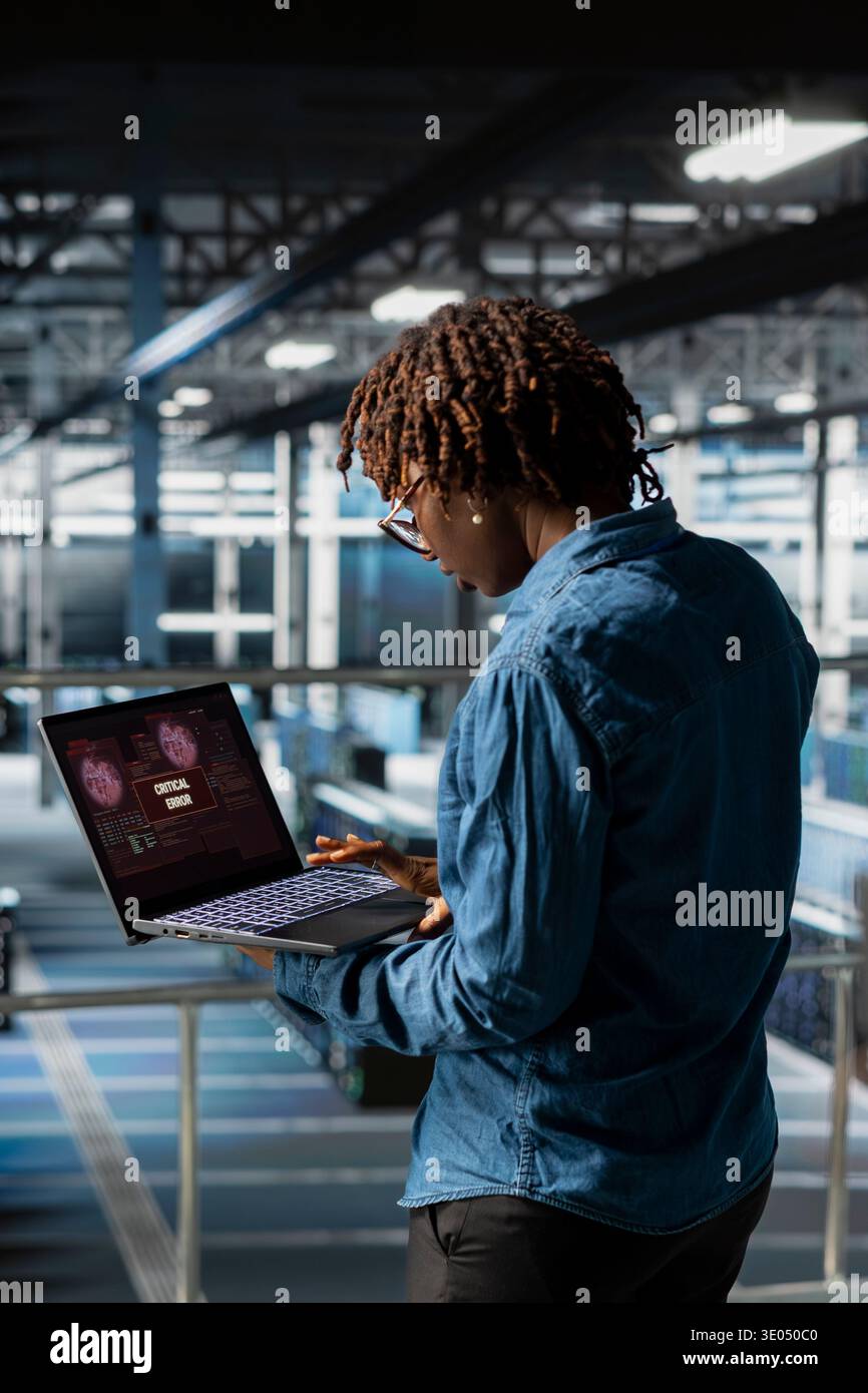 Un ingegnere del software nero si fa prendere dal panico dopo aver ricevuto un avviso popup di errore critico sullo schermo del notebook. Esperto donna di server hub avvisato di bug che causano basse prestazioni hardware, rapporto diagnostico. Foto Stock