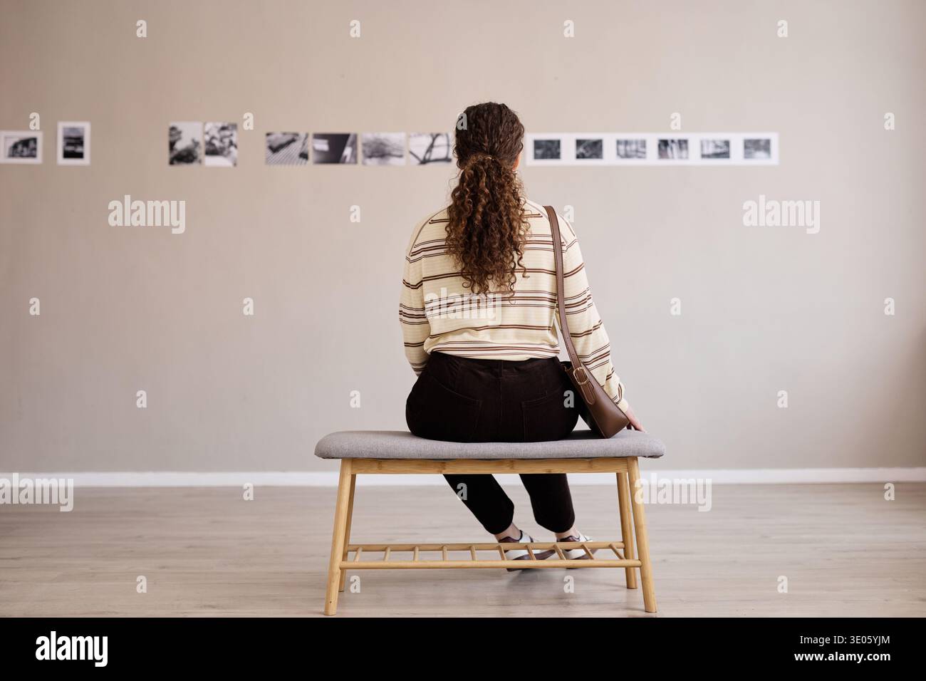 Giovane donna caucasica seduto da sola osservando le fotografie nella galleria d'arte Foto Stock