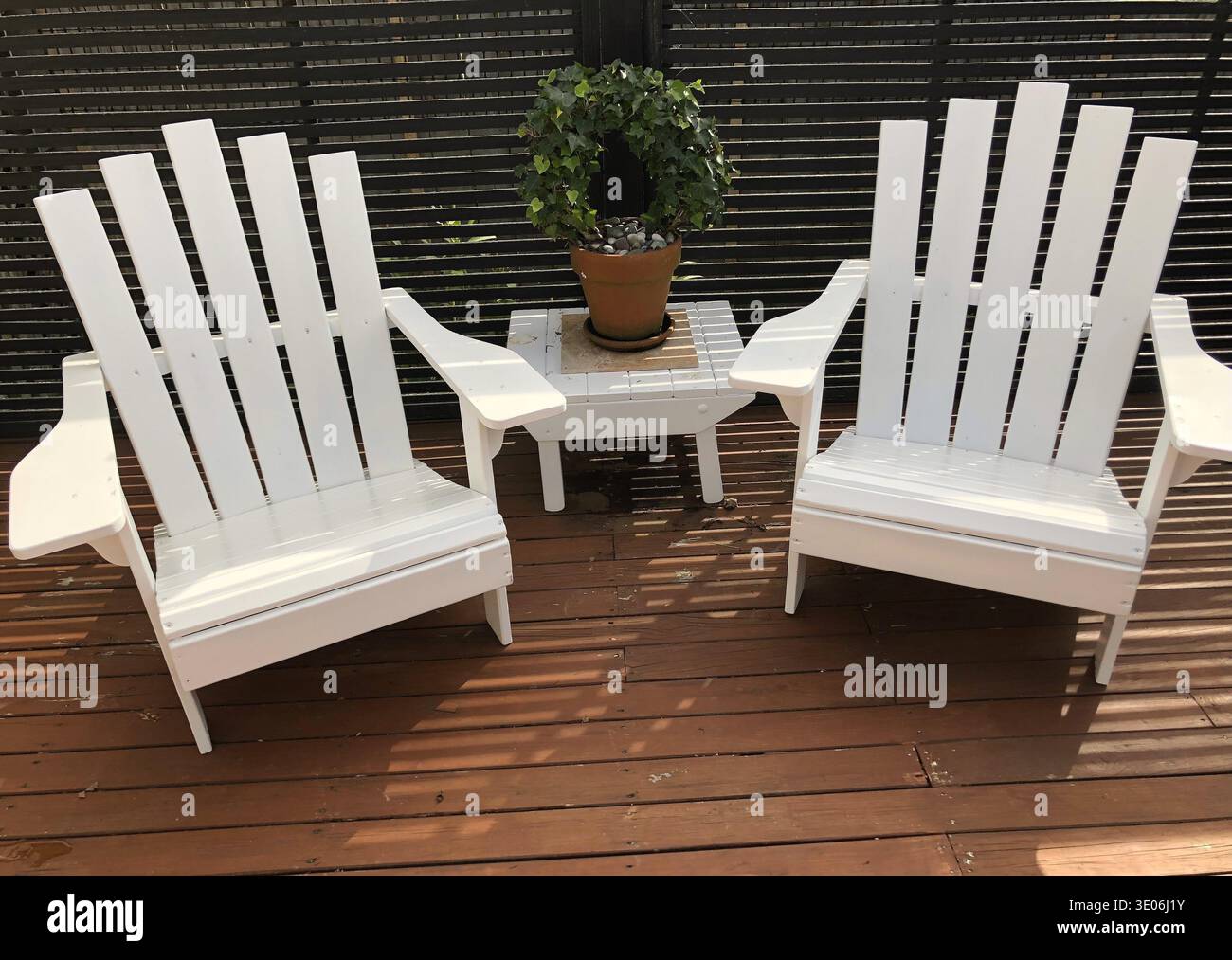 Sedie bianche Adirondack sul ponte di legno con pianta in vaso Foto Stock
