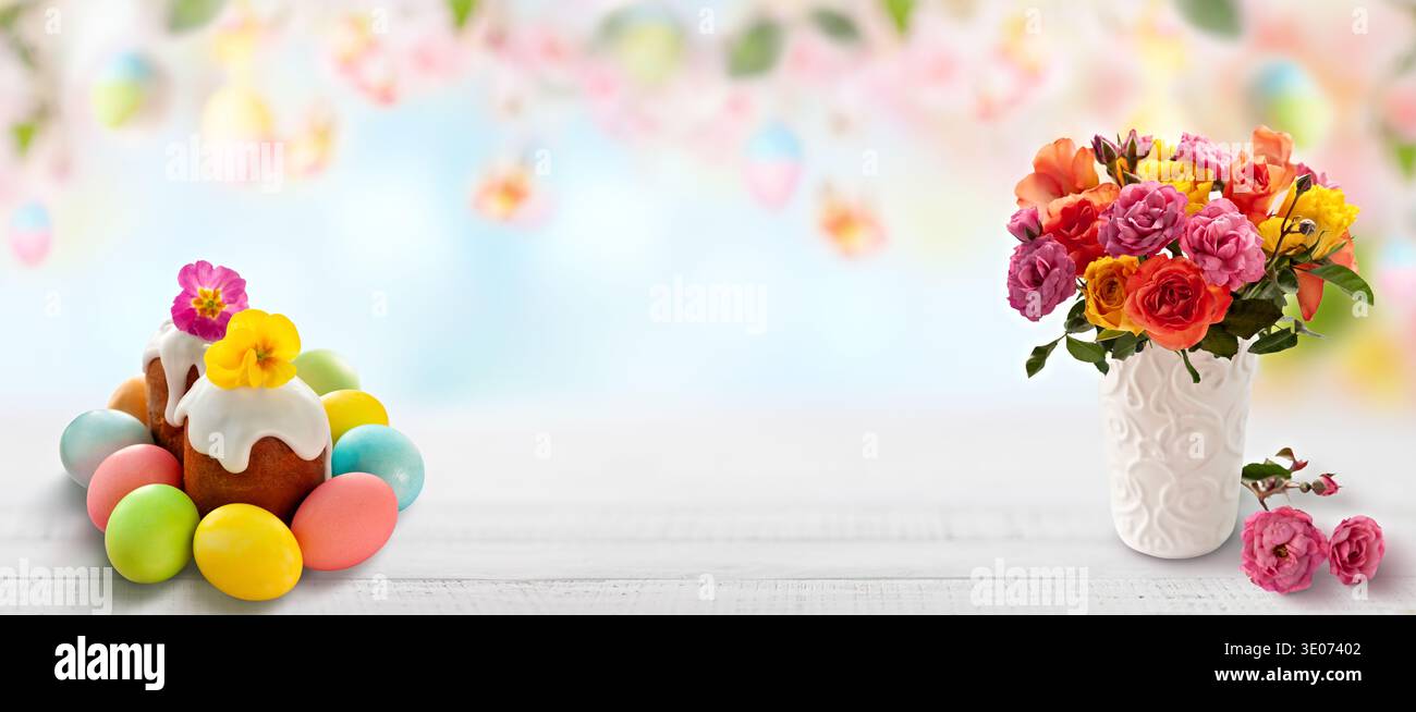 Uno sfondo bianco con una torta e un vaso di fiori. La torta è decorata con uova e i fiori sono in un vaso Foto Stock