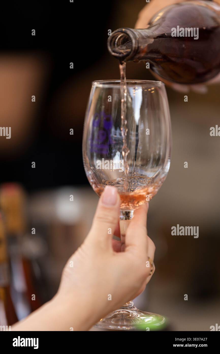 Nel festival Erevan Wine Days, il vino rosato viene versato in un bicchiere di degustazione. Foto Stock