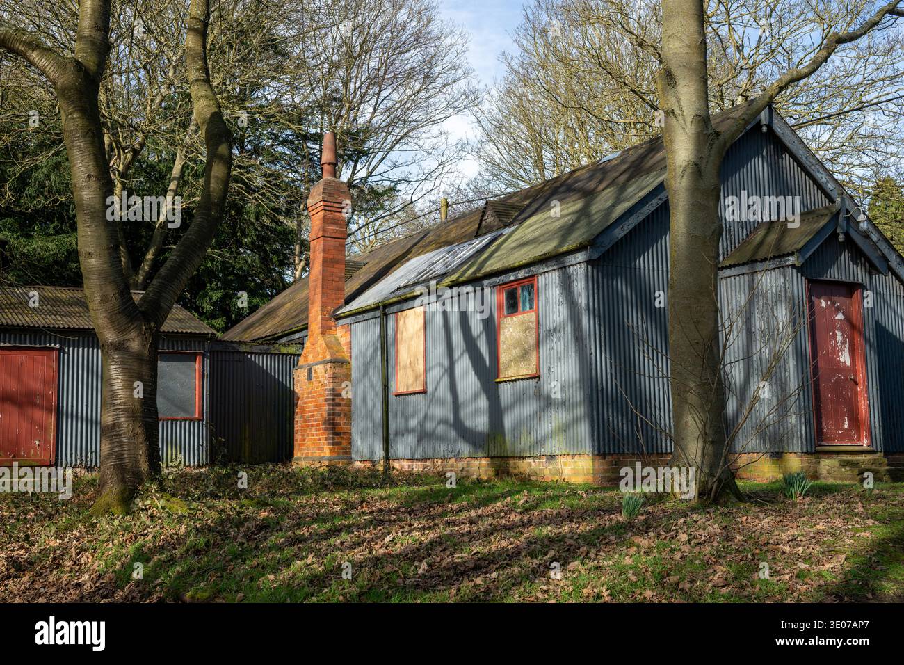 Old Village Hall a Hardwick Village, Clumber Park, Nottinghamshire, Inghilterra, storico edificio in ferro ondulato con camino in mattoni in un ambiente boschivo Foto Stock