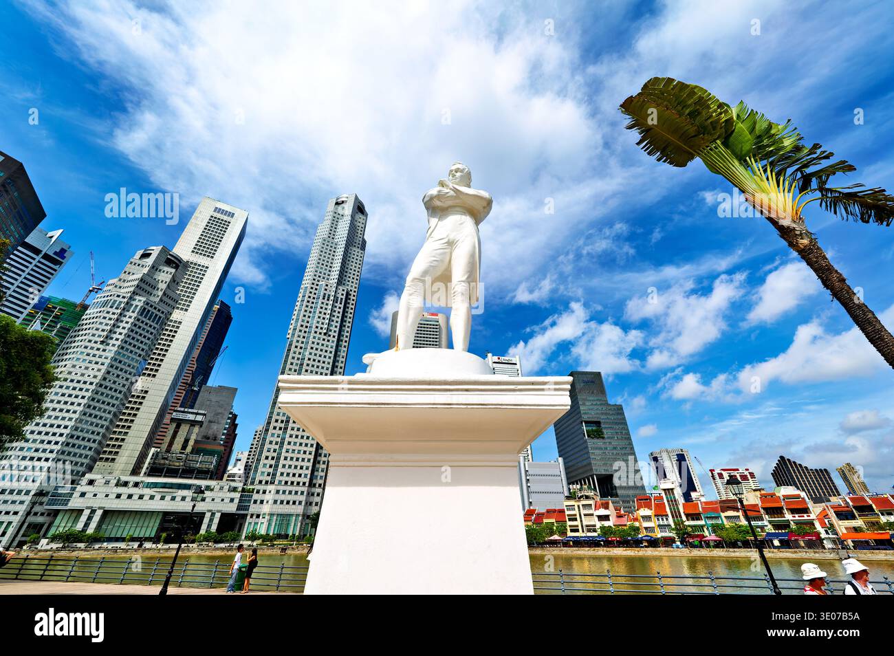 La gente cammina intorno al sito di atterraggio di Raffles a Singapore. Edifici alti circondano l'area sotto un cielo luminoso con nuvole. Foto Stock