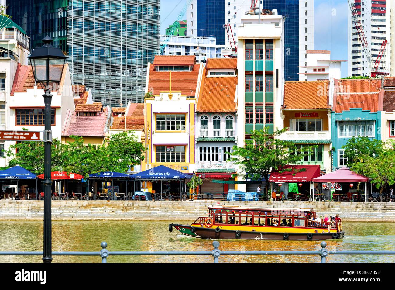 Le persone fanno una gita in barca sul fiume mentre ammirano gli edifici e la vita del centro di Singapore lungo il lungomare. Foto Stock