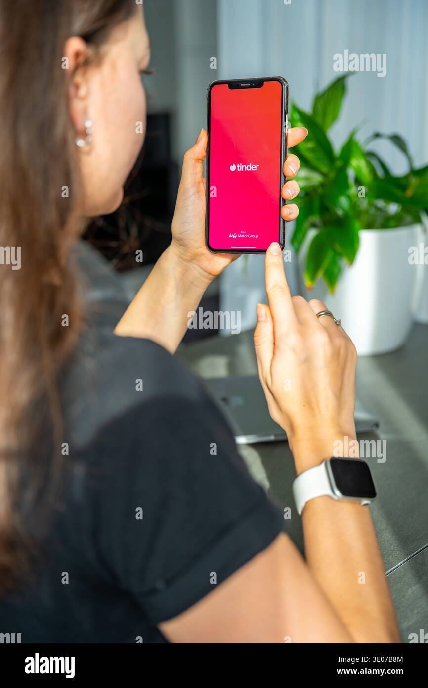 Praga, Repubblica Ceca - 19 febbraio 2026: Primo piano di una donna che tiene le mani sullo smartphone con l'app Tinder aperta sullo schermo. Interazione di incontri online e. Foto Stock