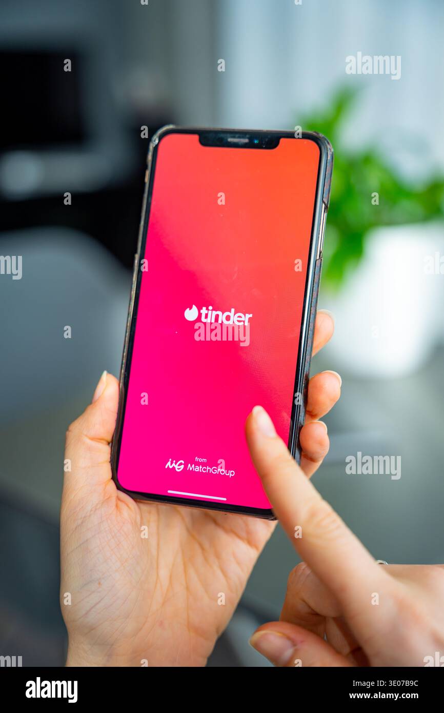 Praga, Repubblica Ceca - 19 febbraio 2026: Primo piano di una donna che tiene le mani sullo smartphone con l'app Tinder aperta sullo schermo. Interazione di incontri online e. Foto Stock