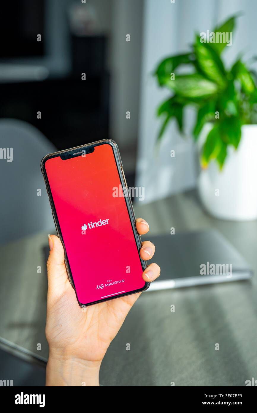 Praga, Repubblica Ceca - 19 febbraio 2026: Primo piano di una donna che tiene le mani sullo smartphone con l'app Tinder aperta sullo schermo. Interazione di incontri online e. Foto Stock