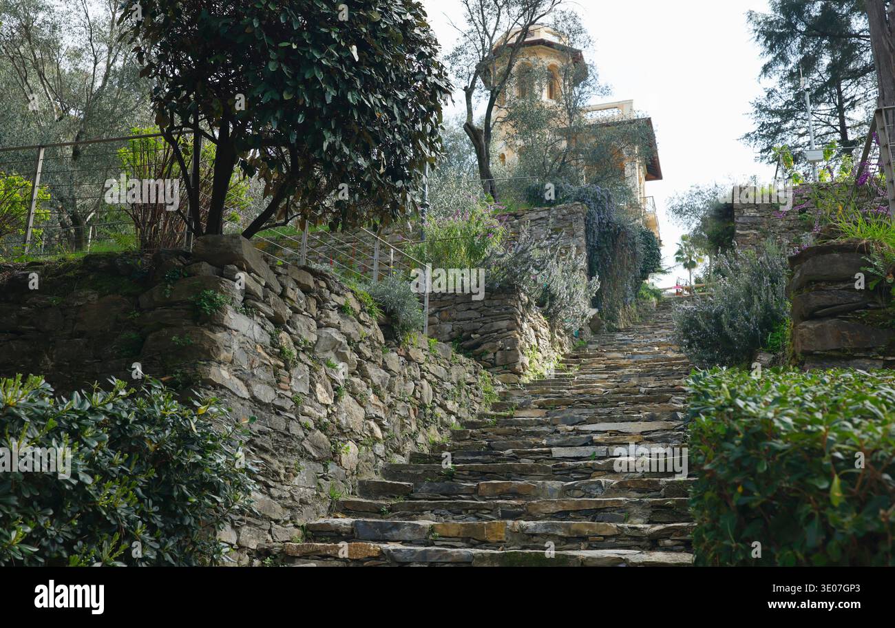 Storica scalinata in pietra che conduce alla torre gialla nel Parco di Villa Rocca. Vista prospettica di gradini rustici delimitati da tradizionali muretti a secco Foto Stock