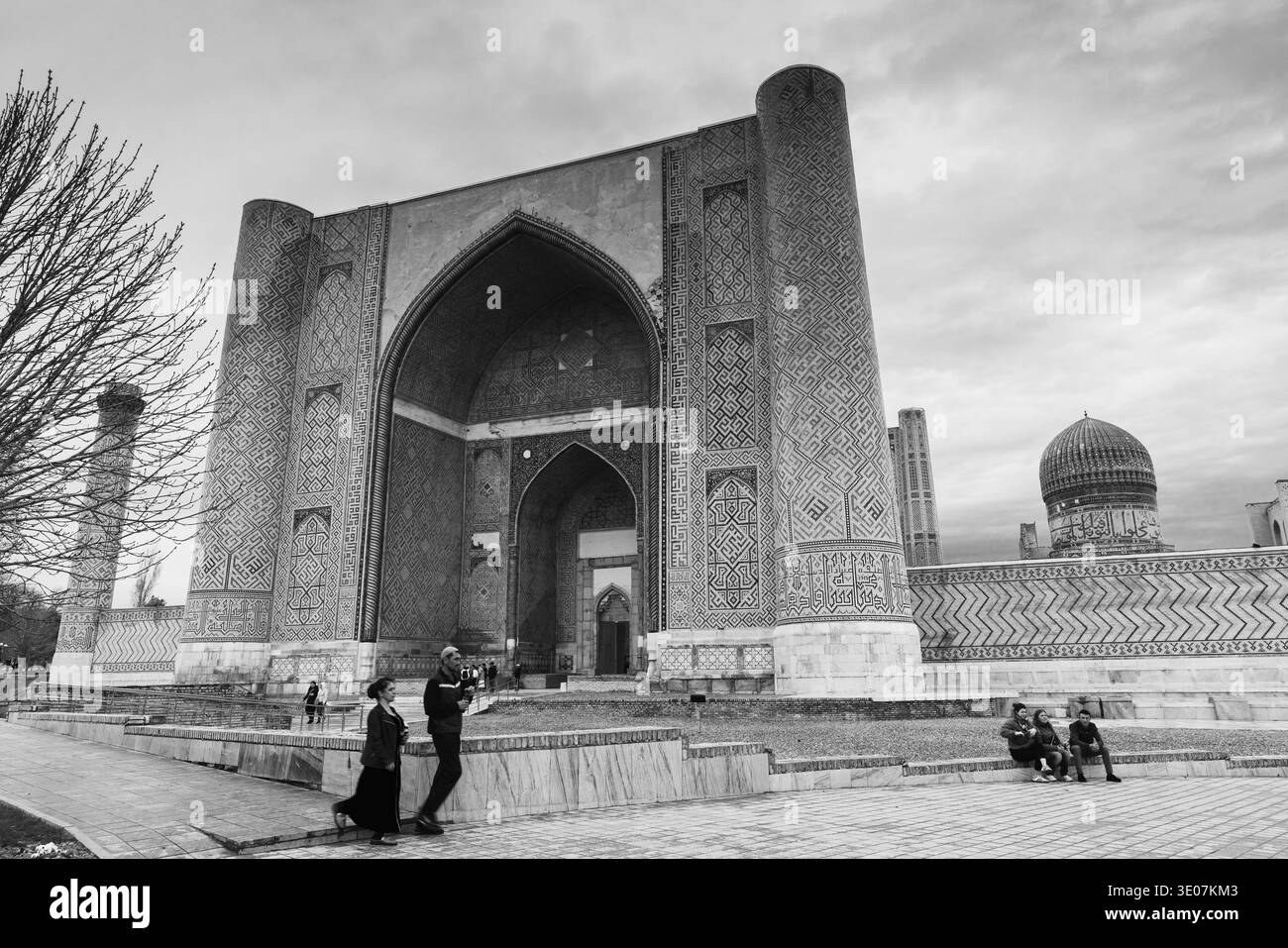 Samarcanda, Uzbekistan - 29 marzo 2024: Moschea di Bibi-Khanym, ingresso principale esterno del portale in una giornata buia e nuvolosa, i turisti camminano per la strada Foto Stock