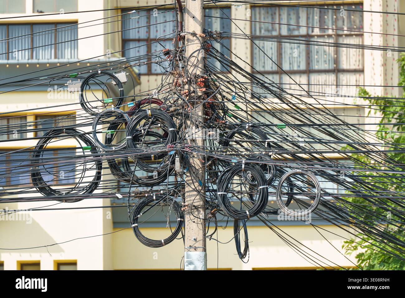 Cavo di alimentazione e comunicazione, telefono, cavo Internet aggrovigliati sul palo elettrico in periferia Foto Stock