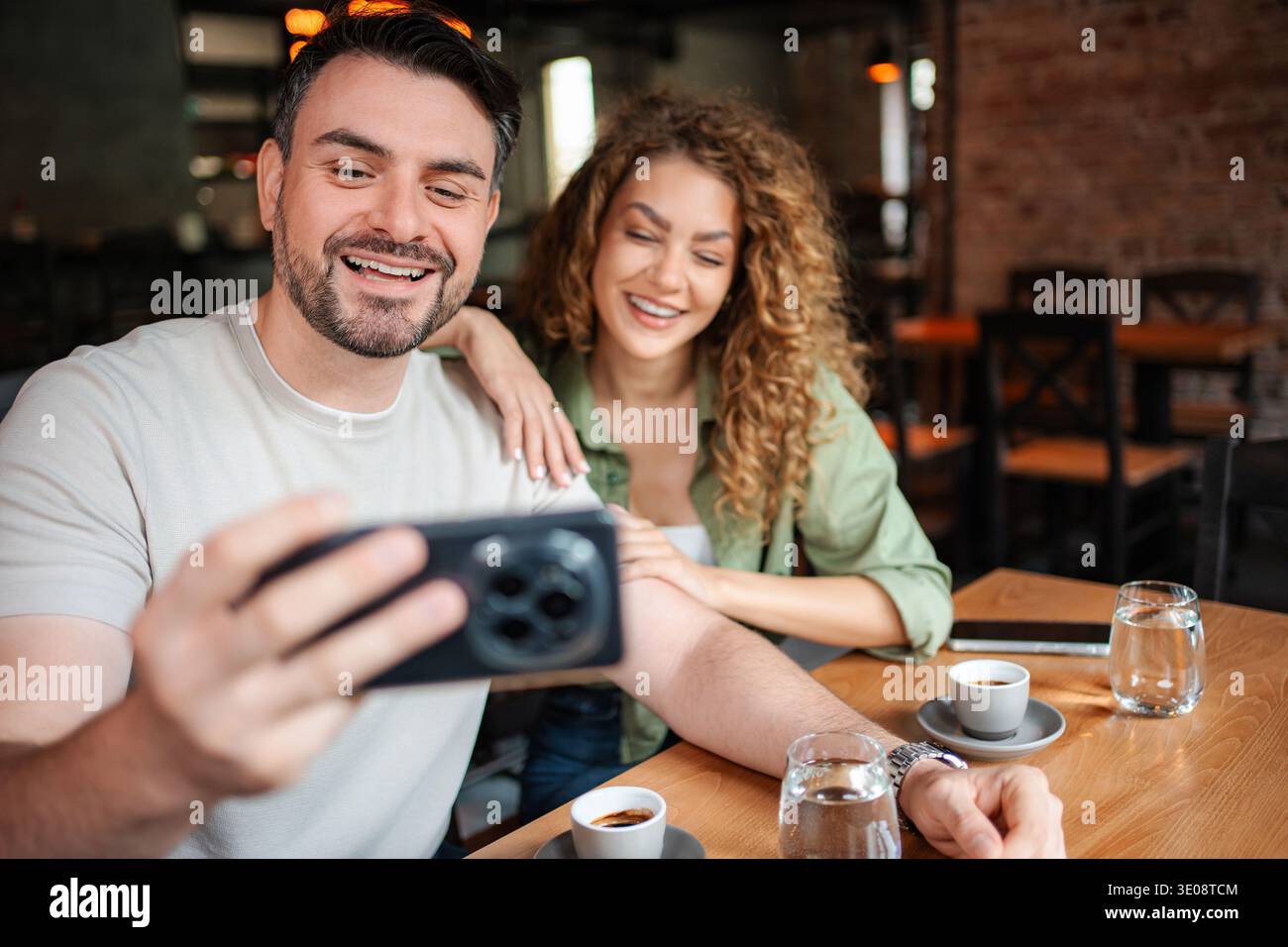 Coppia felice che si fa un selfie mentre beve un caffè in un bar Foto Stock