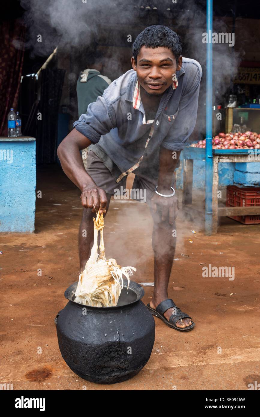 Uomo che brucia un pollo per strada, Odisha, India Foto Stock