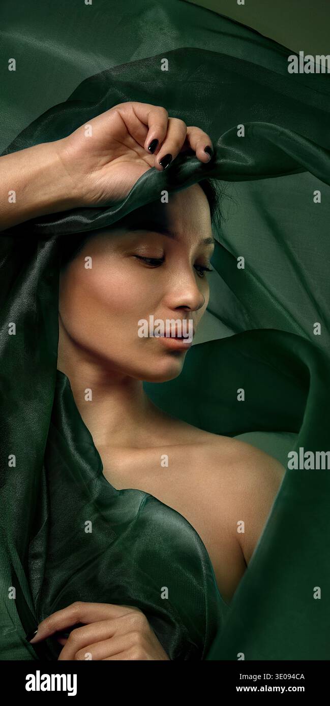 Ritratto di bellezza di donna asiatica avvolta in tessuto di seta verde fluente Foto Stock
