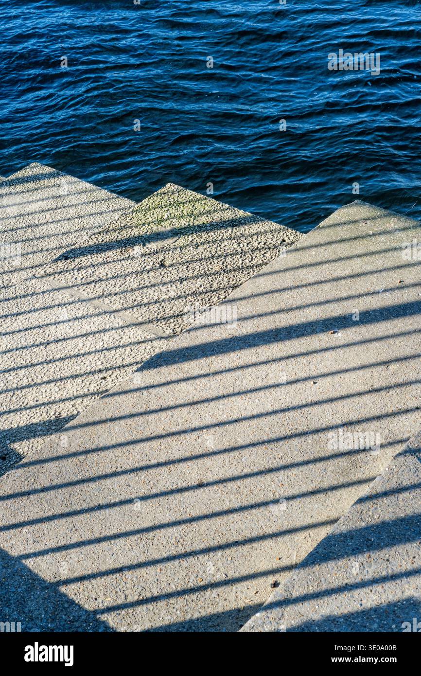 Luce del sole e ombra su gradini di pietra con il fiume oltre Foto Stock