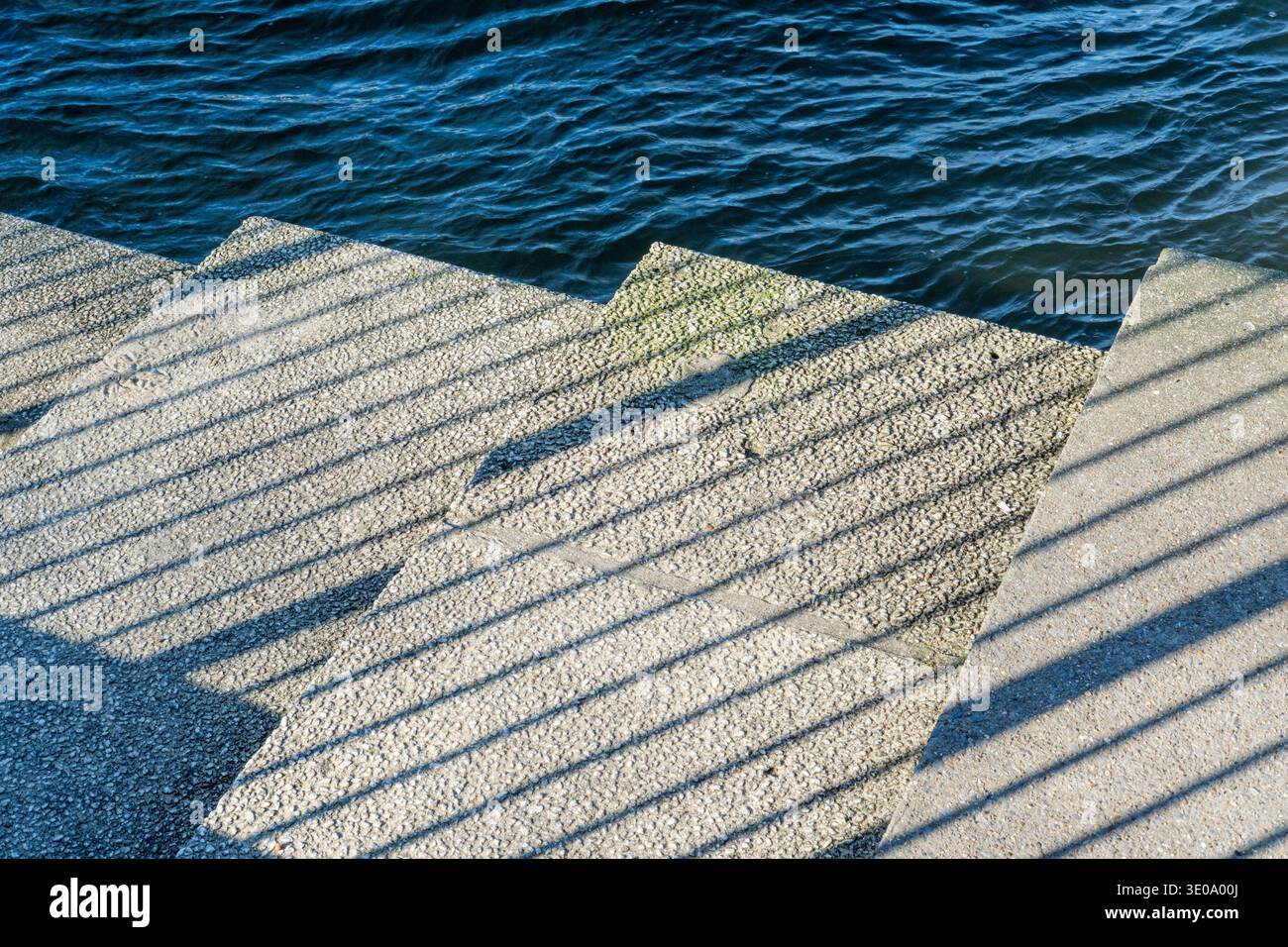 Luce del sole e ombra su gradini di pietra con il fiume oltre Foto Stock