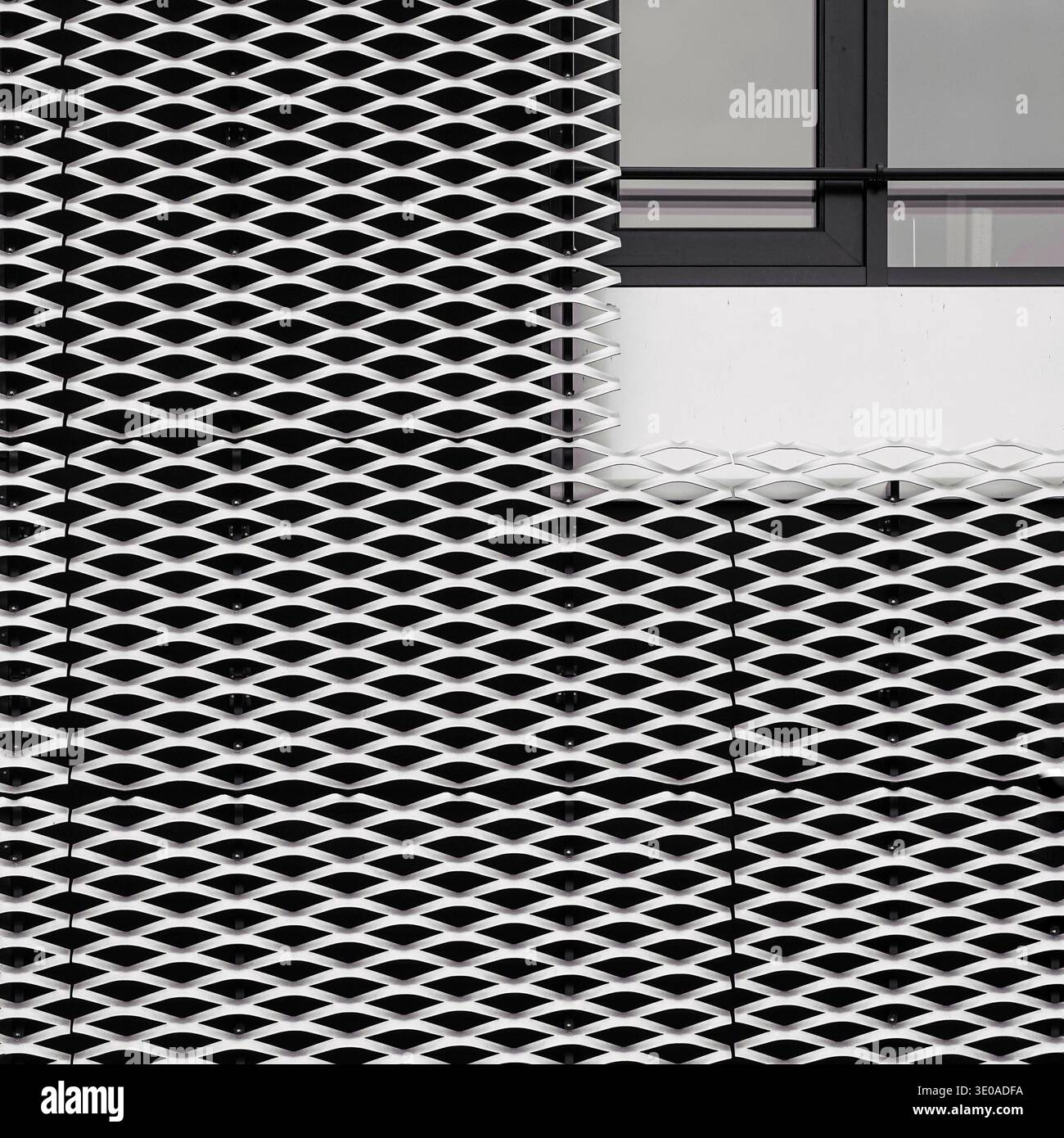 Dettagli architettonici minimalisti di rete metallica espansa bianca che si intersecano con una cornice scura della finestra e una parete nera. Foto Stock