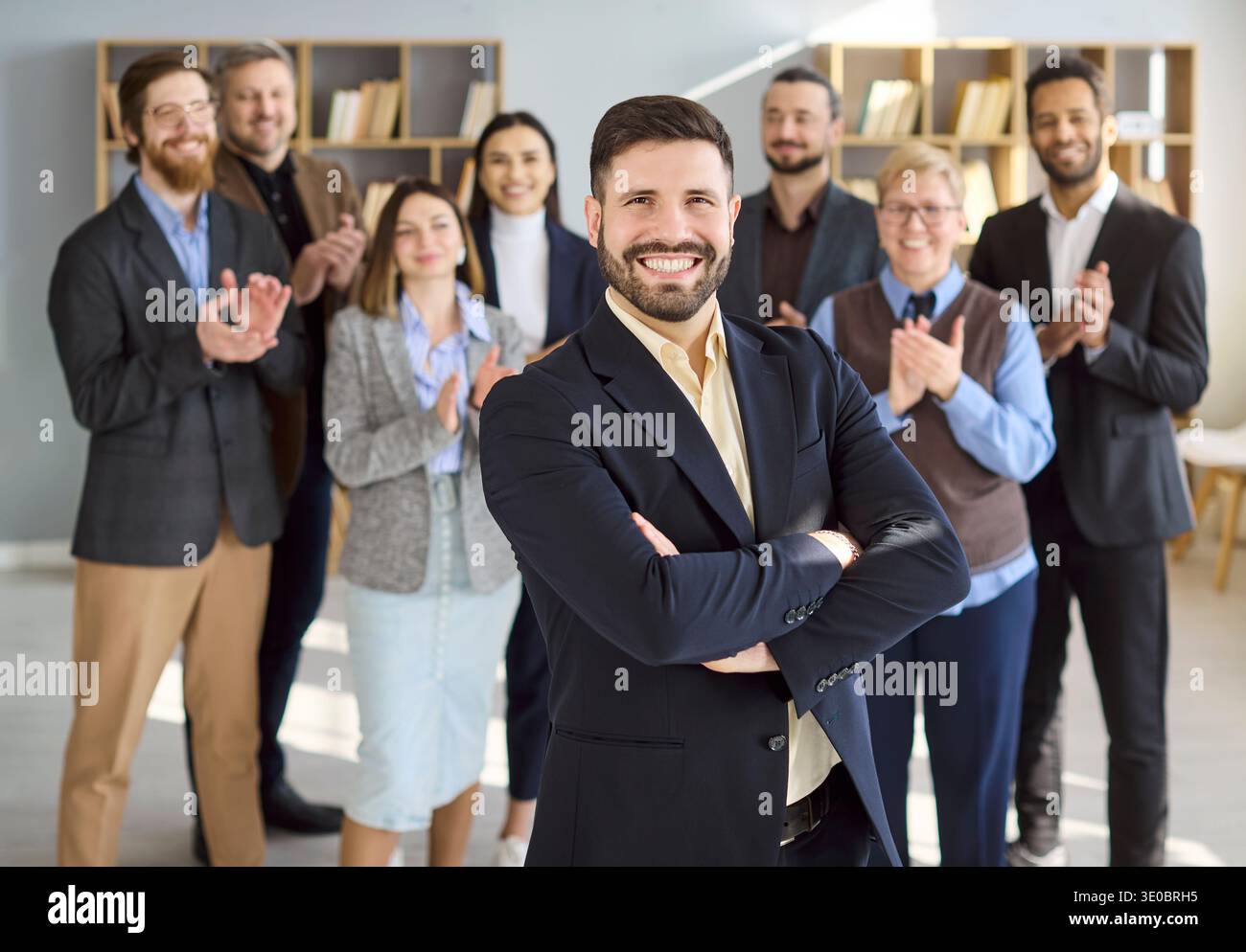Giovane uomo d'affari fiducioso con un team che applaude per la crescita professionale Foto Stock
