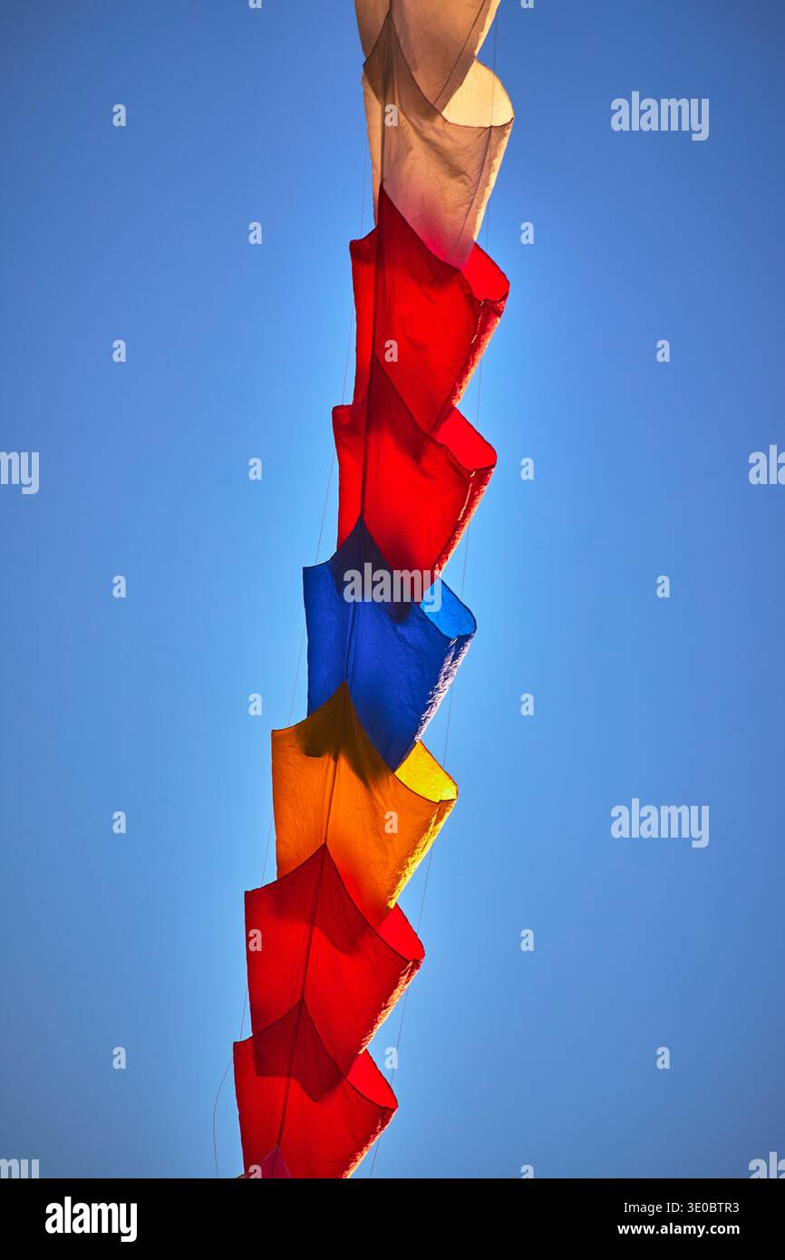 Catena di aquiloni colorati contro il cielo blu al Festival degli aquiloni Foto Stock