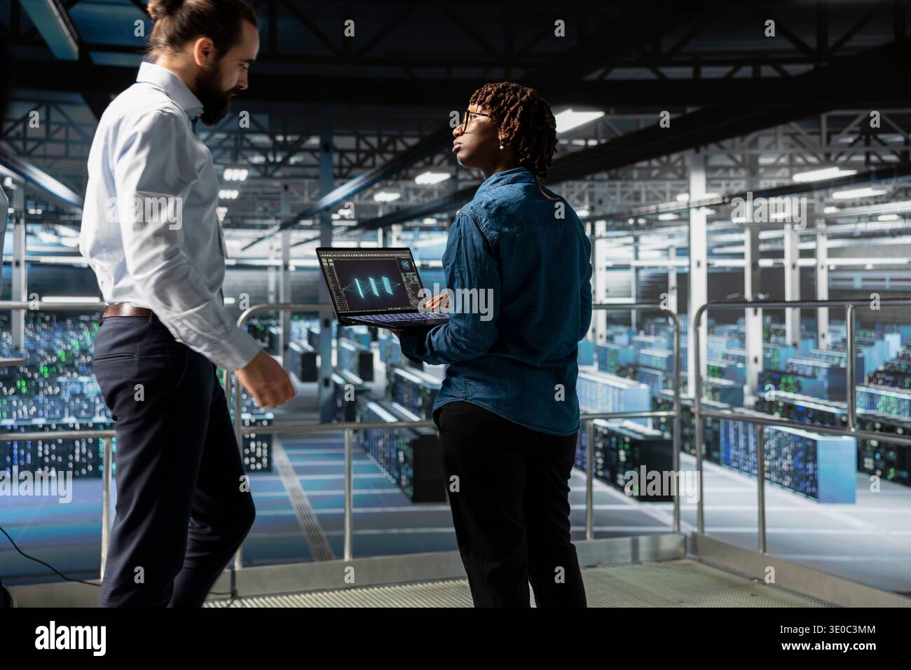 Ingegneri neri che eseguono la diagnostica su laptop utilizzando strumenti di monitoraggio del sistema per identificare gli errori, eseguendo brainstorming per la codifica. Gli esperti IT collaborano per prevenire i guasti e ridurre al minimo i tempi di inattività. Foto Stock