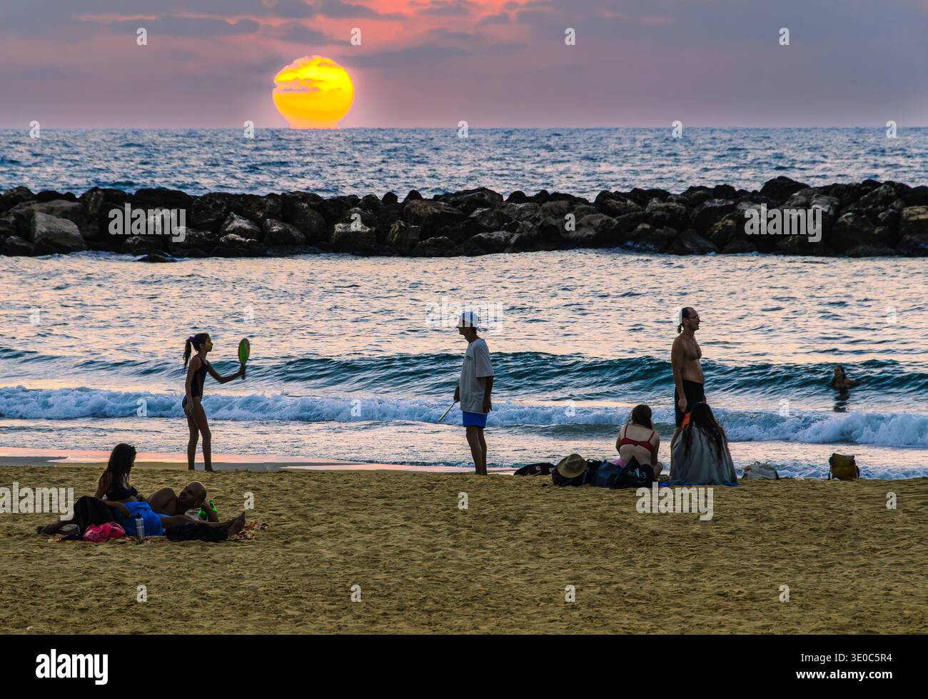 I giovani giocano a paddleball (matkot) sulla spiaggia di Tel Aviv al tramonto 1 Foto Stock