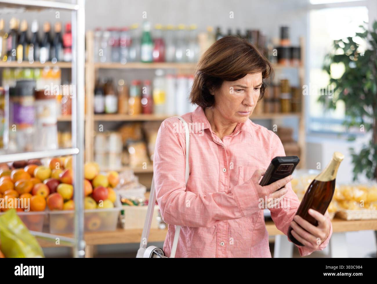 L'acquirente donna esegue la scansione del codice QR sull'etichetta della birra nel negozio di alimentari Foto Stock