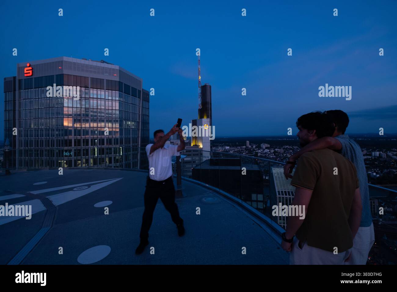 17.08.2025, Germania, Francoforte sul meno, Assia - piattaforma panoramica sulla TORRE PRINCIPALE, dipendente cordiale che scatta una foto ricordo per i giovani turisti Foto Stock