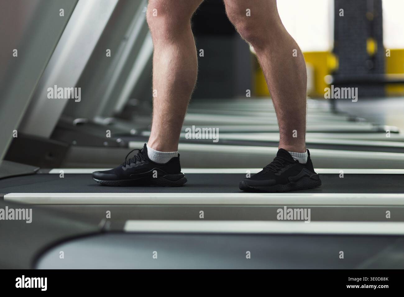 Primo piano delle gambe del fitness che camminano sul tapis roulant in palestra Foto Stock