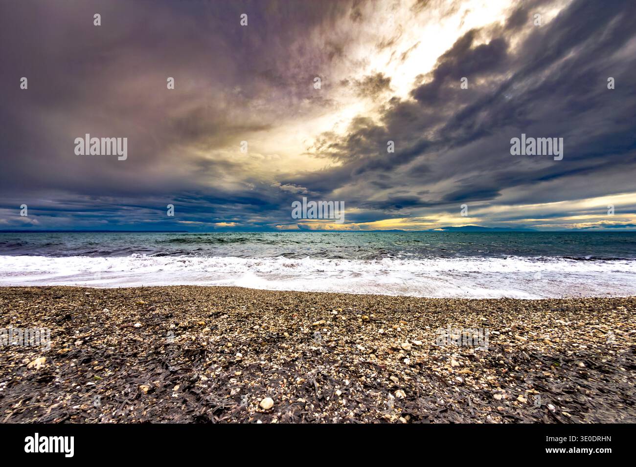 Spettacolare panorama marino serale presso la spiaggia Paralia Portaria in Calcidica, Macedonia centrale, Grecia. Nuvole di tempesta scure sul Golfo delle Terme con onde brea Foto Stock