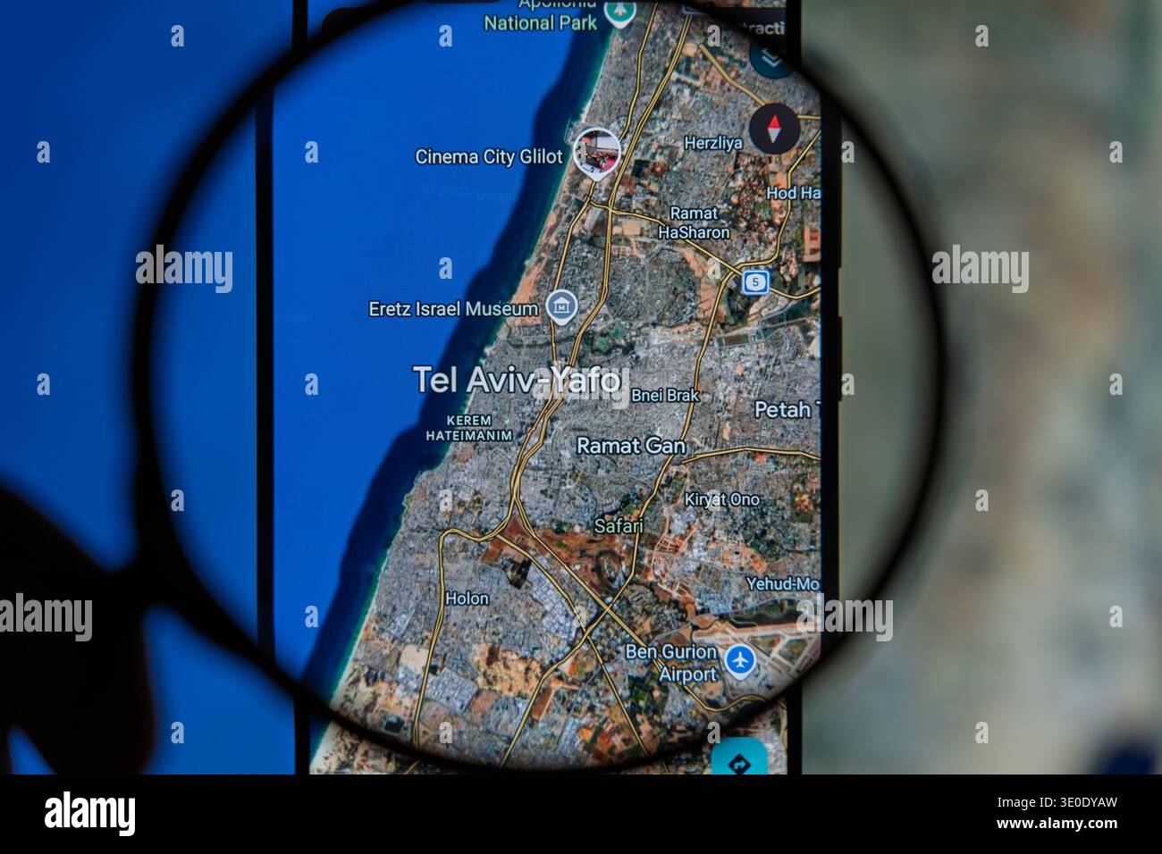 Lente di ingrandimento sullo schermo di uno smartphone che visualizza una mappa digitale di Tel Aviv Yafo, evidenziando aree urbane, strade e l'aeroporto Ben Gurion per Foto Stock