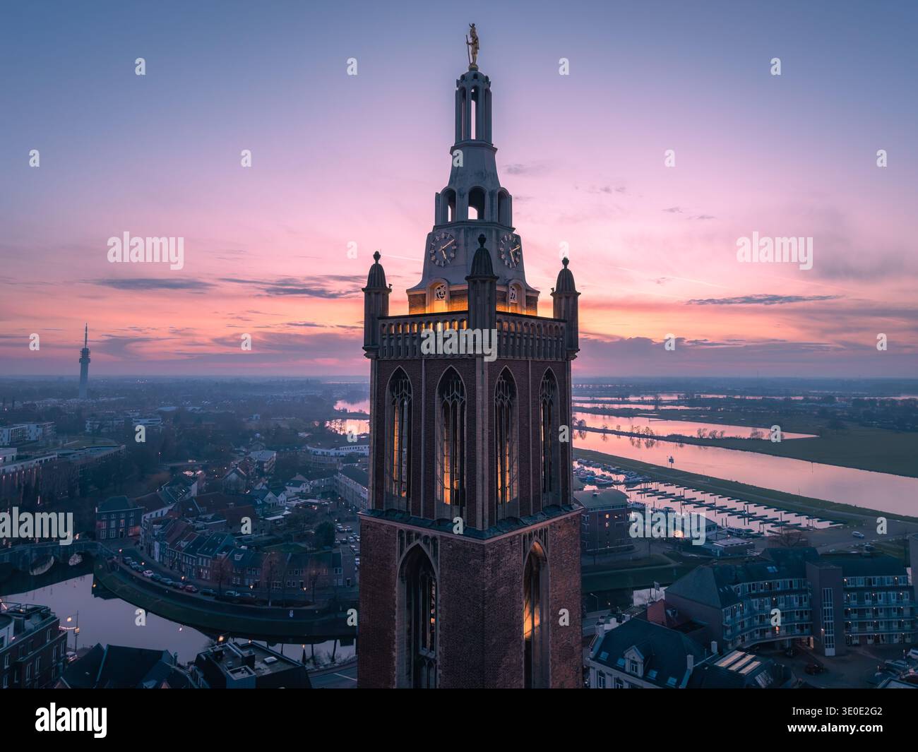 Veduta aerea della torre di St. Christoffelkathedraal, che perfora il cielo oscuro mentre il sole tramonta sul fiume Maas, Roermond, Limburgo, Paesi Bassi. Foto Stock