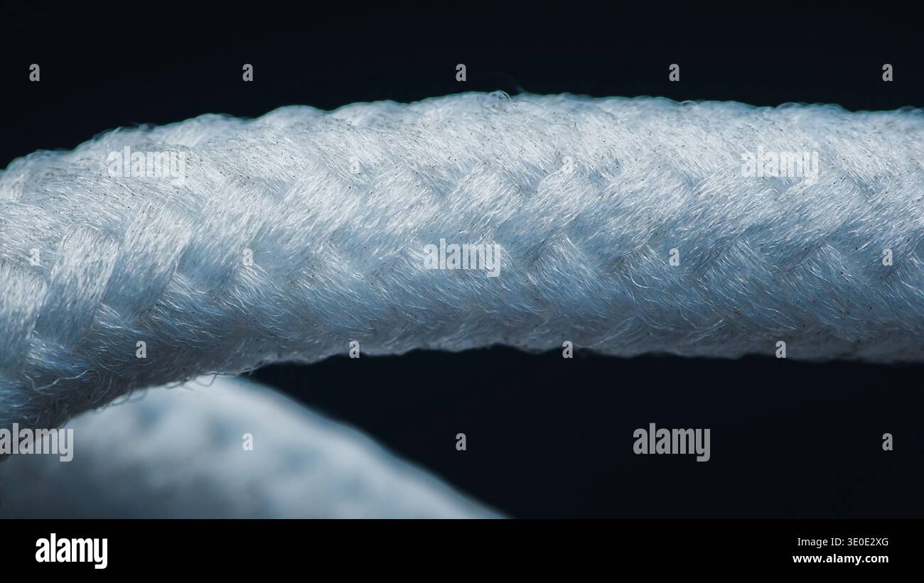 Dettagli in corda nautica bianca, che mostrano un primo piano della struttura intrecciata resistente e delle fibre testurizzate su uno sfondo scuro. Fotografia, niente generativ Foto Stock