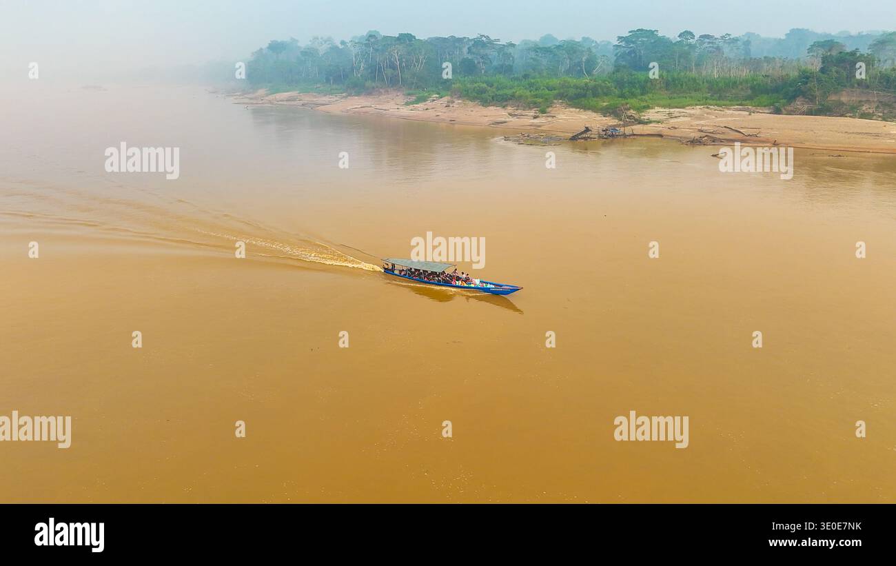 Vista aerea di una barca che taglia le acque fangose del fiume madre de Dios, incorniciata dalla nebbiosa e verdeggiante foresta pluviale, Puerto Maldonado, madre de Foto Stock