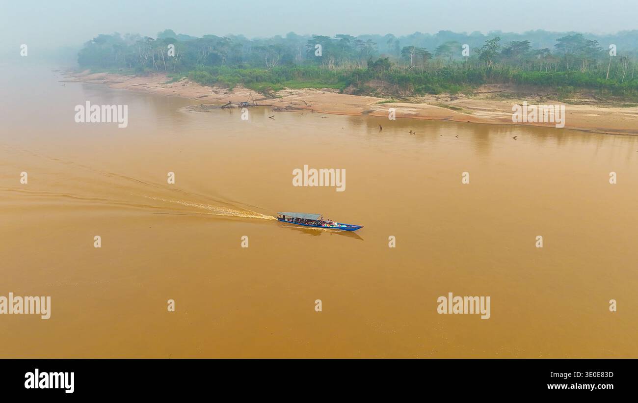 Vista aerea di una barca che affonda le acque fangose del fiume, lasciando una veglia sullo sfondo della lussureggiante e verde foresta pluviale amazzonica, Puerto Maldona Foto Stock