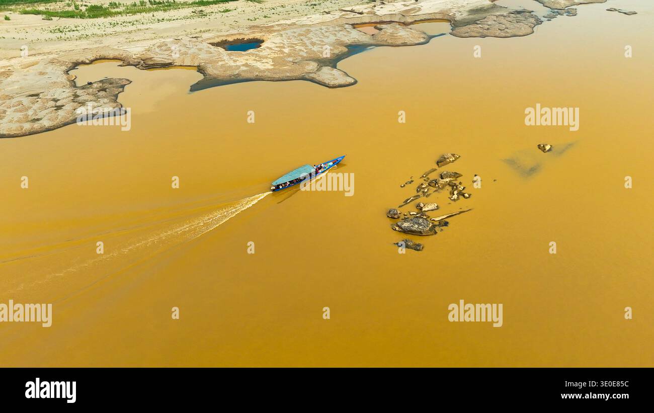 Vista aerea di una barca che affetta attraverso il fiume fangoso, giustapposta alle rive sabbiose, Puerto Maldonado, madre de Dios, Perù. Foto Stock