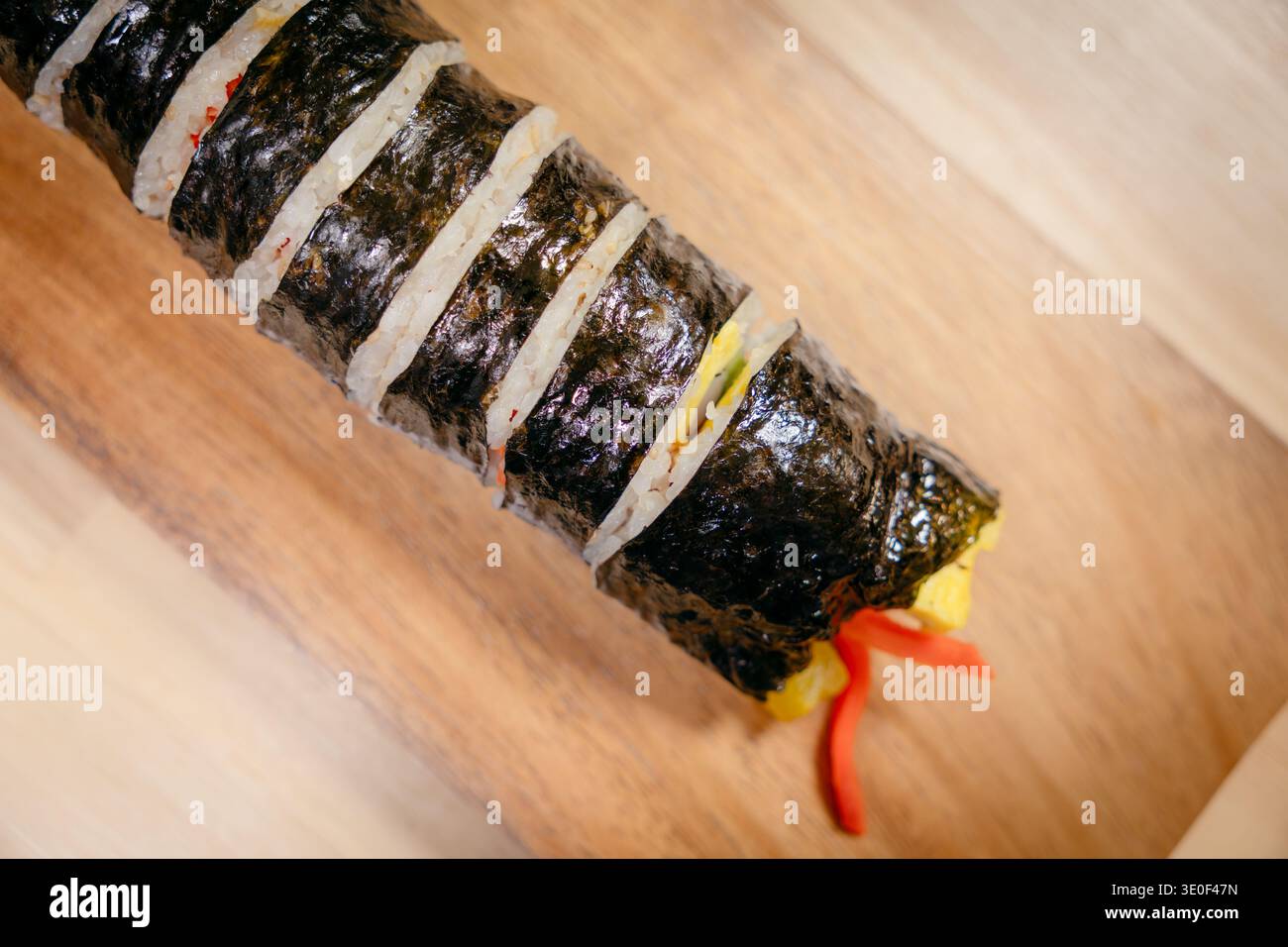 Rotolo di gimbap coreano a fette su un asse di legno Foto Stock