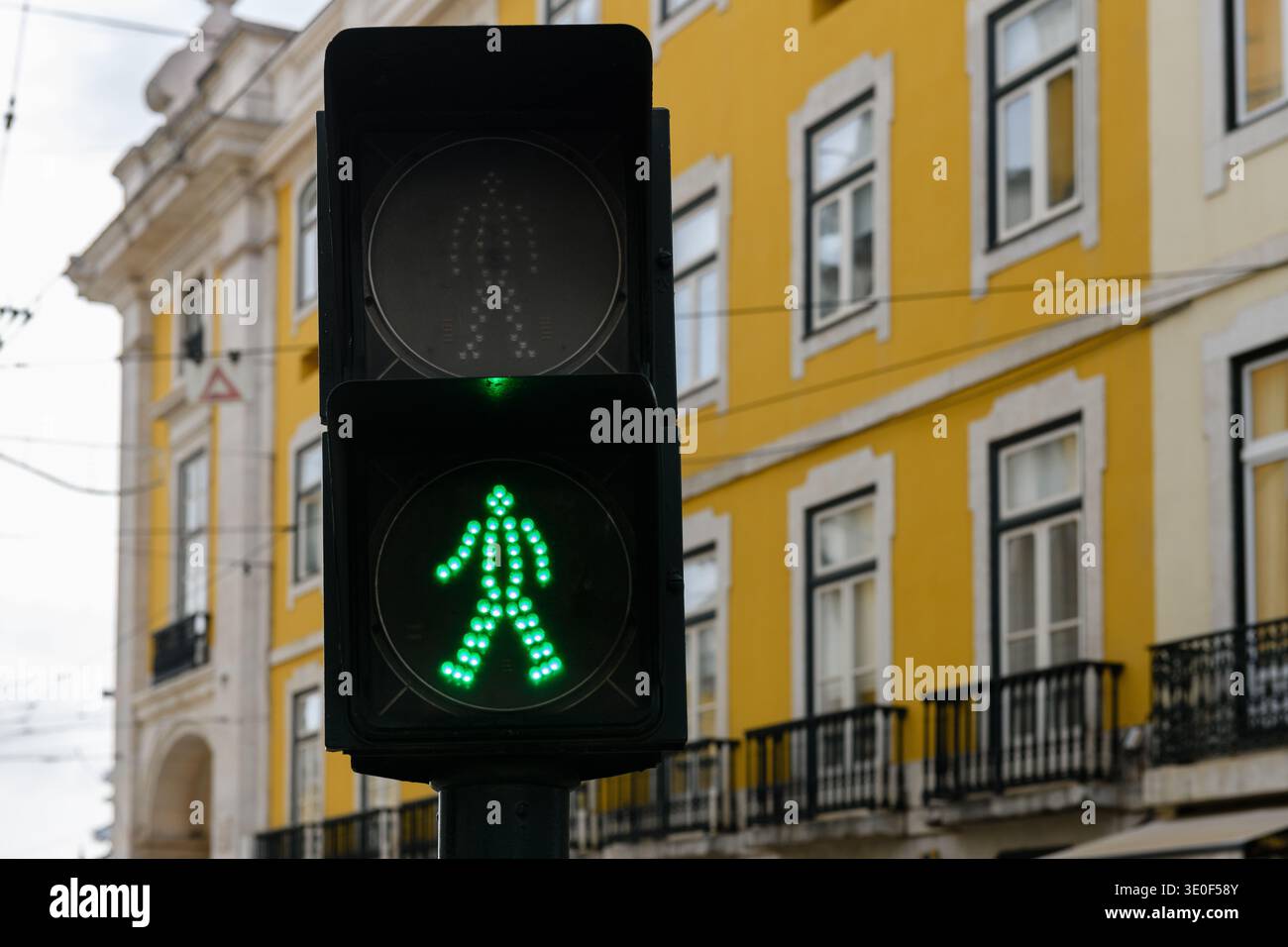 Semaforo verde per pedoni su una strada di Lisbona con un camminatore verde che indica che è sicuro per i pedoni attraversare la strada. Foto Stock
