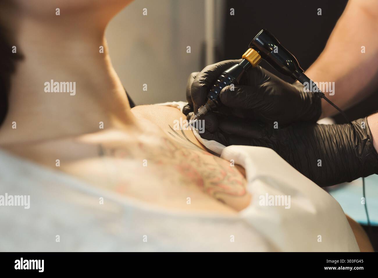 Tatuatore che lavora con ago sul corpo dei clienti Foto Stock