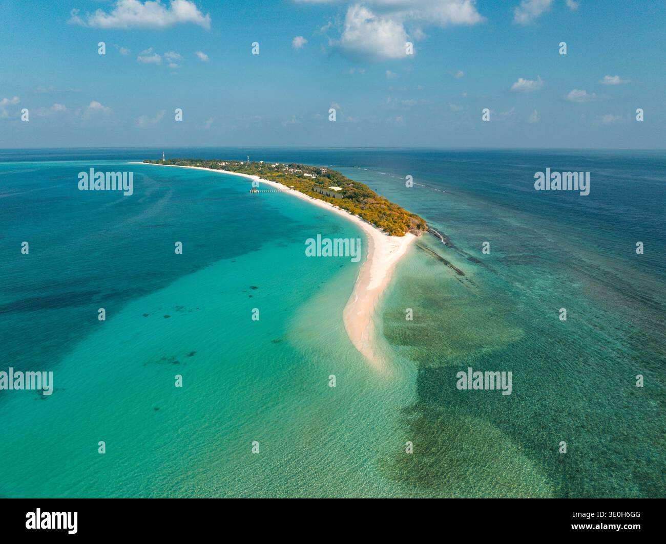 Vista aerea di un'isola slanciata abbracciata dal mare turchese, dove la spiaggia di sabbia incontra l'orizzonte, Vashafaru, Haa Alif, Malediven. Foto Stock