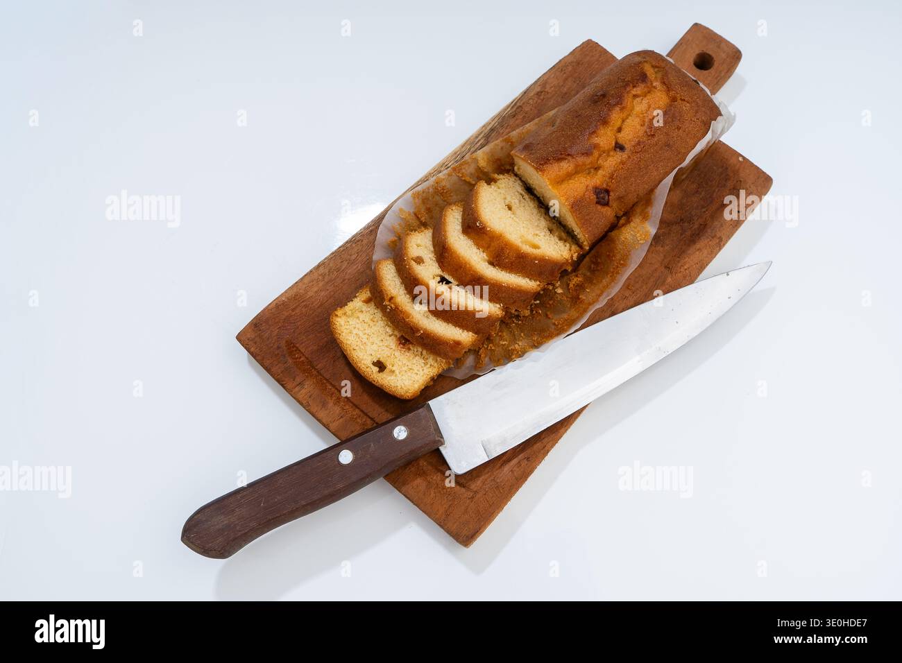 Torta fatta in casa a fette, preparata su un tagliere in legno rustico con un coltello, pronta per servire o per spuntini Foto Stock