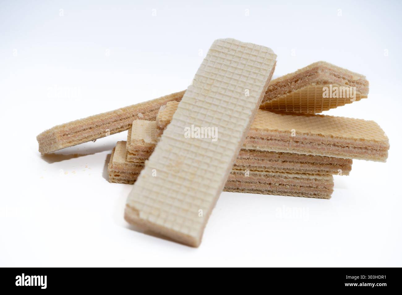 Wafer impilati su uno sfondo bianco, con strati croccanti e ripieno di panna, che rappresentano un dolce piacere e un dessert Foto Stock