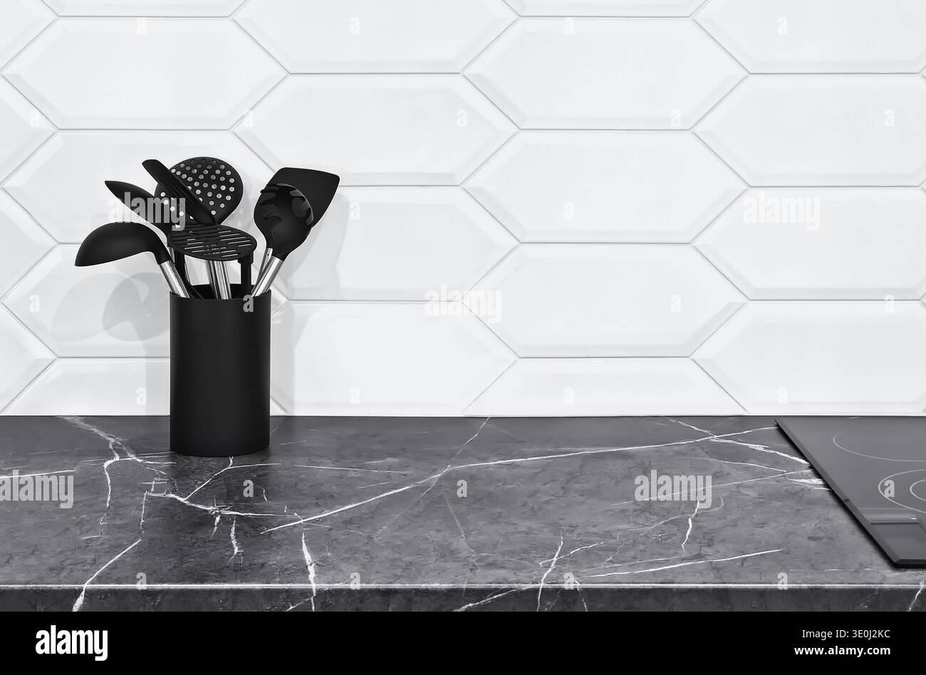 Gli interni moderni e minimalisti della cucina presentano un elegante ripiano in marmo bianco e una parete bianca con motivi geometrici. Un contenitore di stoviglie nere provi Foto Stock