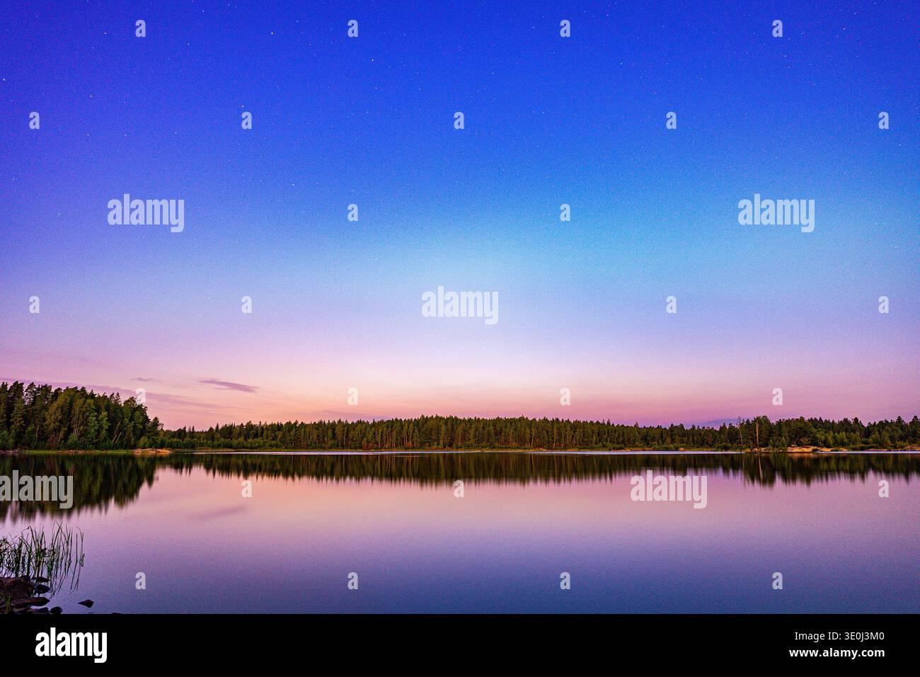 "Lago finlandese durante le notti bianche con uno spettacolare tramonto rosa e un perfetto riflesso sull'acqua" Foto Stock