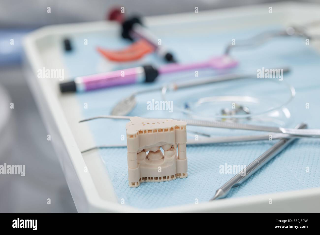 Primo piano del modello di addestramento per impianti dentali con strumenti e materiali disposti su vassoio sterile in una moderna clinica odontoiatrica. Concetto di implantologia e. Foto Stock