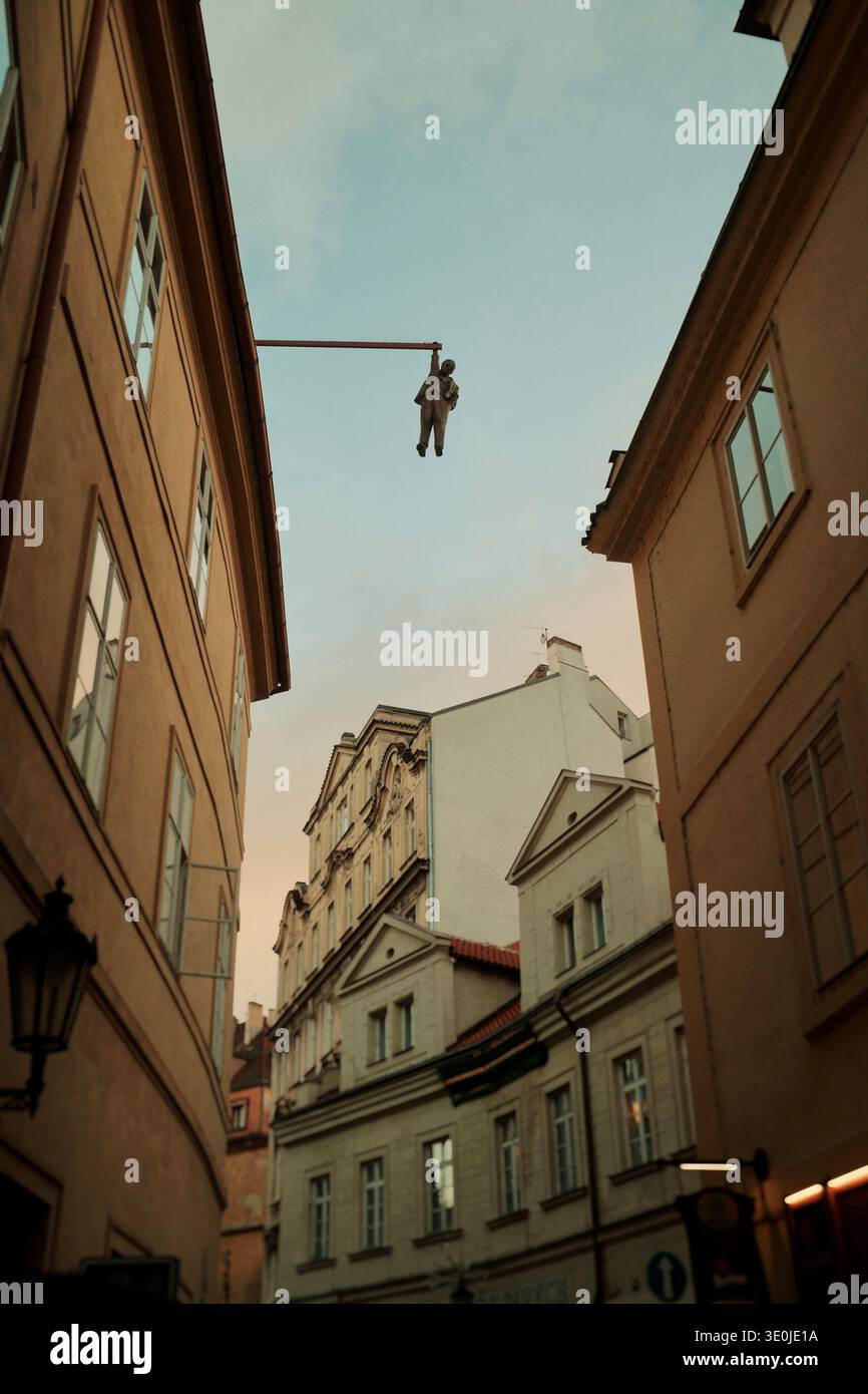 Stretta strada storica con la classica architettura di Praga e l'uomo che appende la statua nella città vecchia di Praga, Repubblica Ceca. Foto Stock